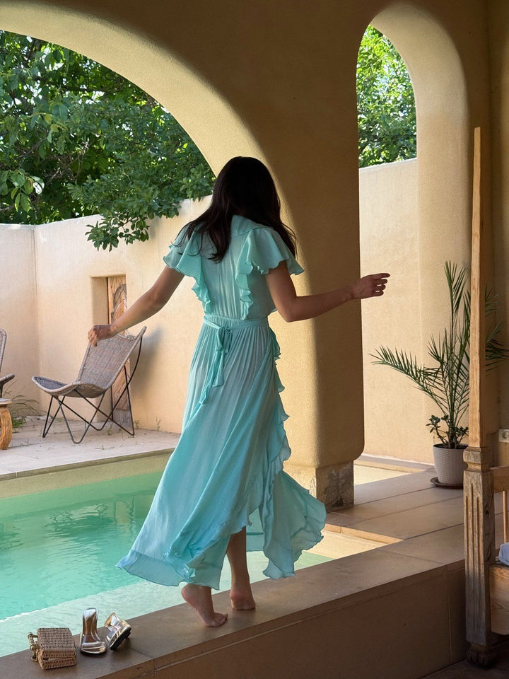 Ariane ruffle wrap maxi in turquoise beside a pool