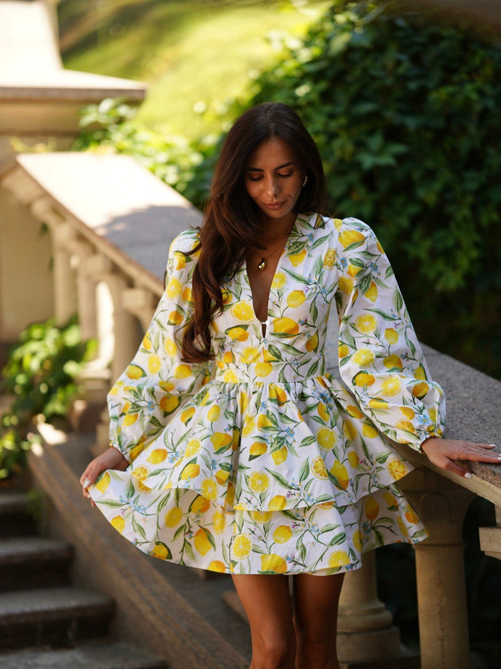 Amalia flounce dress in a lemon print on garden stairs