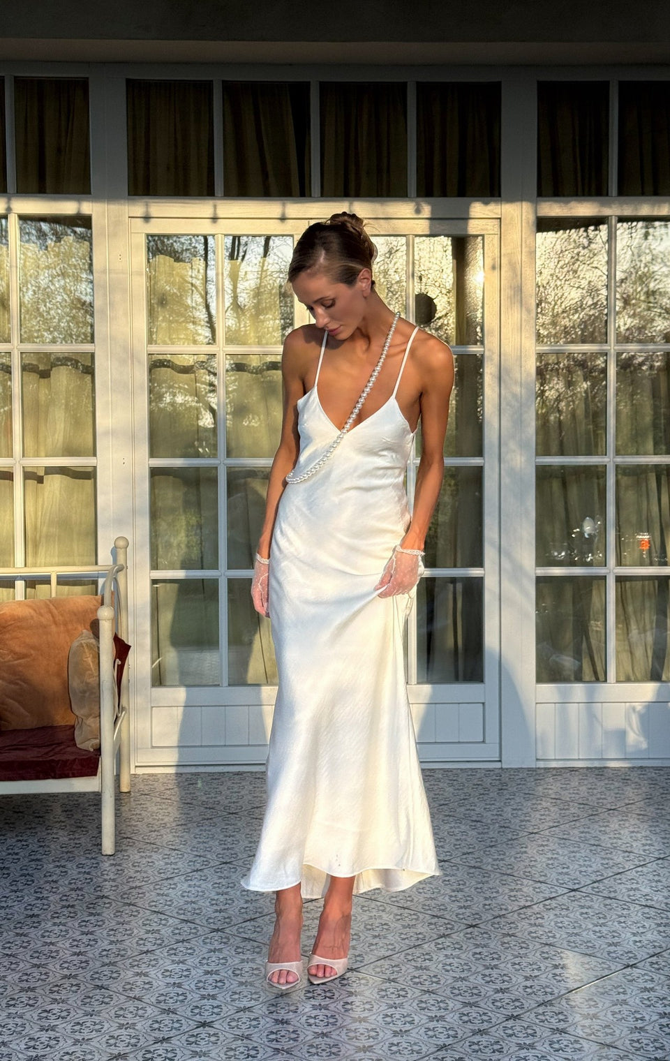 Pierrette open-back satin maxi in milk white on a sunlit terrace
